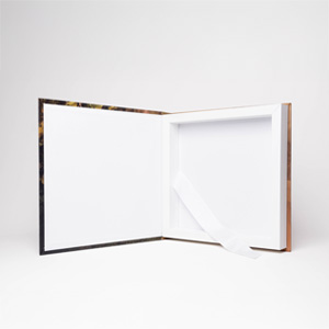 Acompanha fita em cetim na cor branca para auxiliar na retirada do álbum